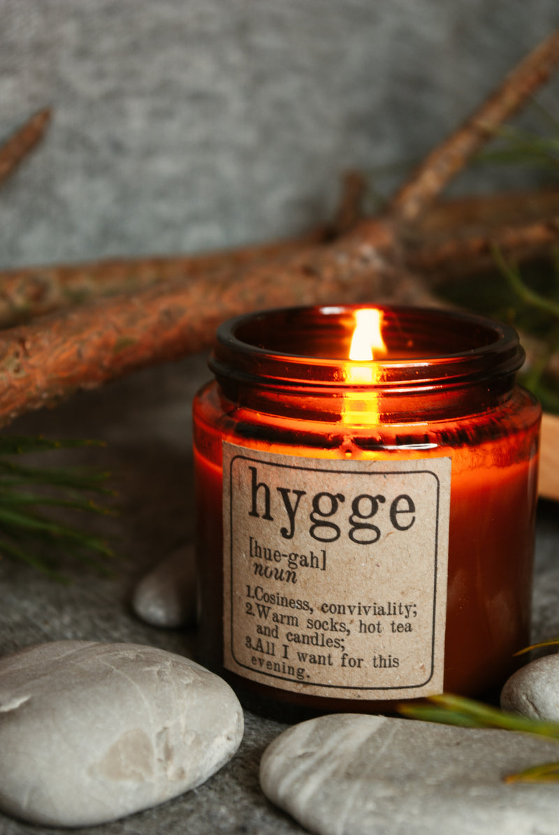 a scented candle for winter 'hygge' feeling good in winter with natural scented candles and aromatherapy. Burring candle in glass jar in dim light with natural stones and twigs