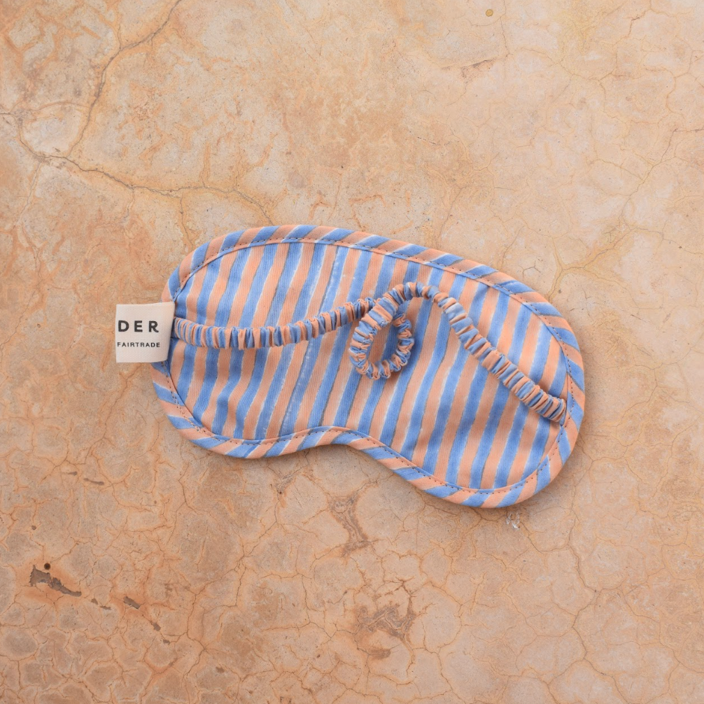Striped sleep mask on a beige textured surface