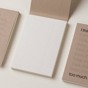 Open dot-grid notepad with neutral cover designs on desk, journalling accessory to help unwind as part of natural sleep remedies.


