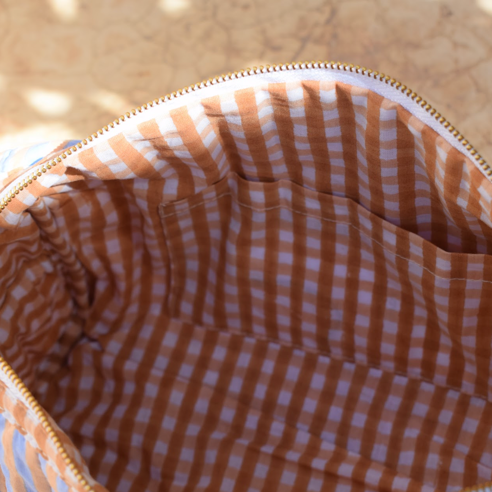 Close-up of a striped bag with a checkered interior on a textured surface.