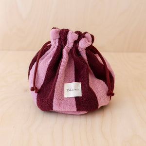 Striped red & pink drawstring bag on a beige/wooden background