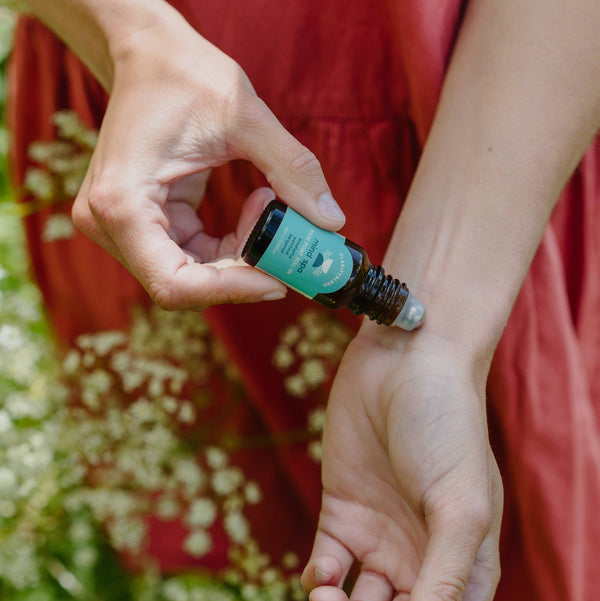 Person applies Clarity Blend Mind Spa pulse point roll-on to wrist outdoors, a simple natural sleep remedies aromatherapy option.

