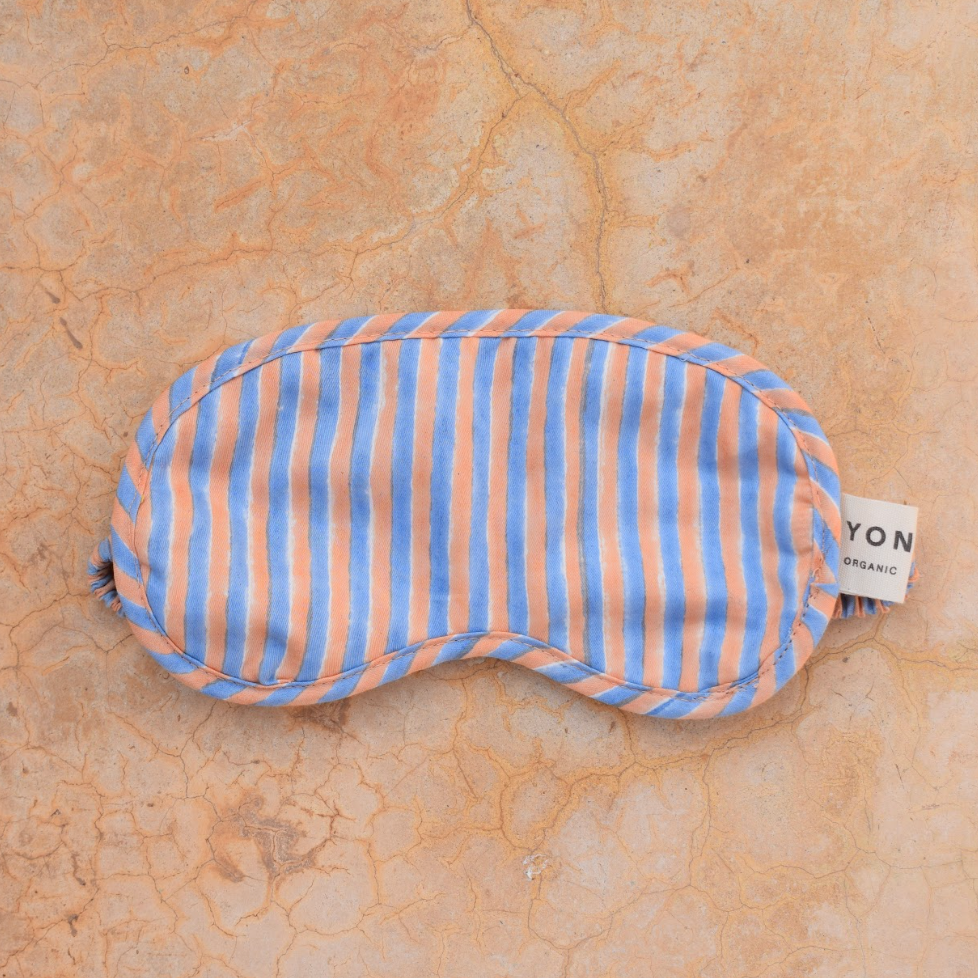 Striped sleep mask on a beige marble surface