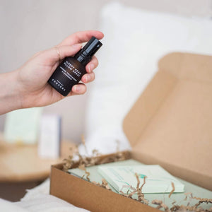 Hand holding Sleepy Head pillow spray by Coopers above an open gift box, a simple bedtime routine item from natural sleep remedies.

