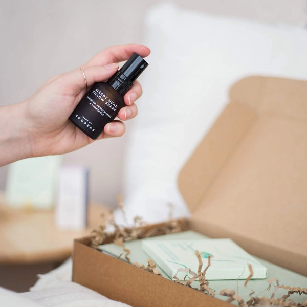 Hand holding Sleepy Head pillow spray by Coopers above an open gift box, a simple bedtime routine item from natural sleep remedies.

