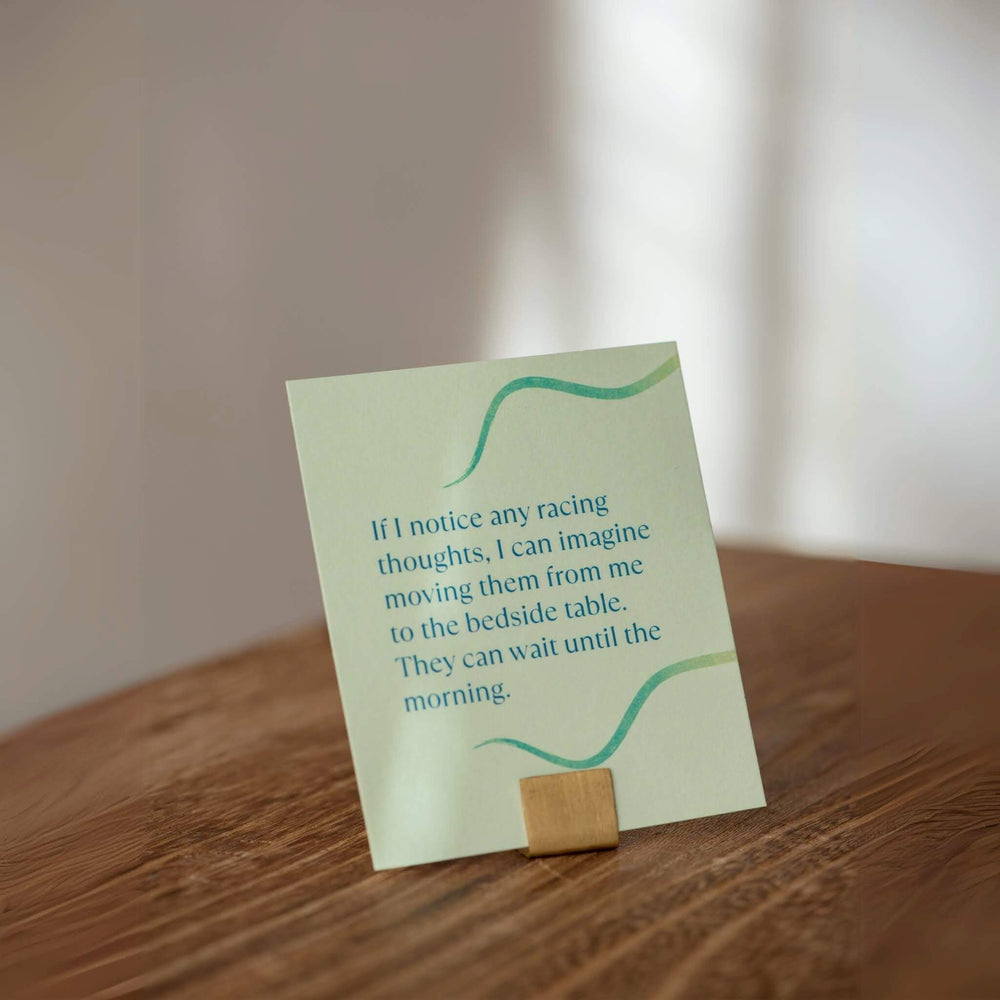 Sleep affirmation card on wooden stand with message about racing thoughts, designed to support calm and natural ways to fall asleep.

