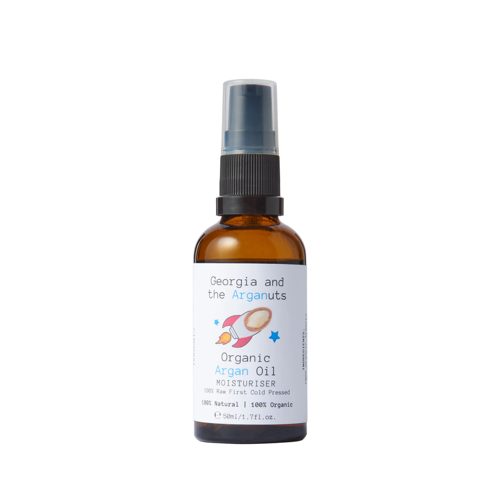 A product image featuring Georgia and the Arganuts Children's Organic Argan Oil Moisturiser in a 50ml packaging. The packaging is predominantly white with blue and star graphics, and a spray pump dispenser.